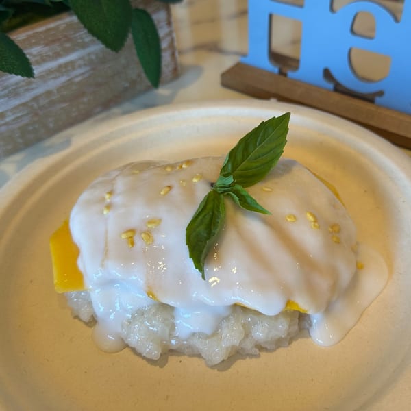 Gen Thai Street Food's mango sticky rice dessert, topped with coconut cream, sesame seeds, and basil.