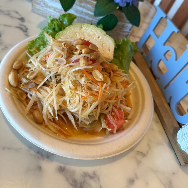 Gen Thai Street Food's papaya salad with peanuts, tomatoes, and cabbage on a white plate.